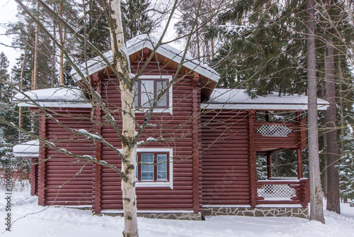 Snow-covered wooden cabin nestled in a forest during winter months in a serene, secluded location photo