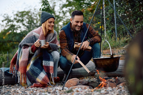 Happy couple cooking over bonfire during their camping trip in nature. photo