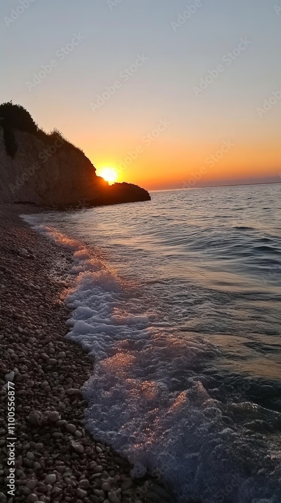 Obraz premium Serene Sunset Over Tranquil Waters, a breathtaking scene showcasing a vibrant sky reflecting warm hues on a quiet sea, gentle waves caressing the sandy beach.