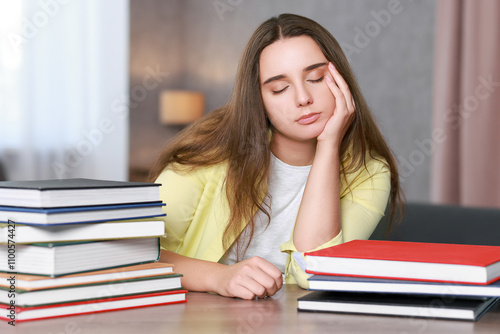 Young student with books having stress before exam at wooden table photo