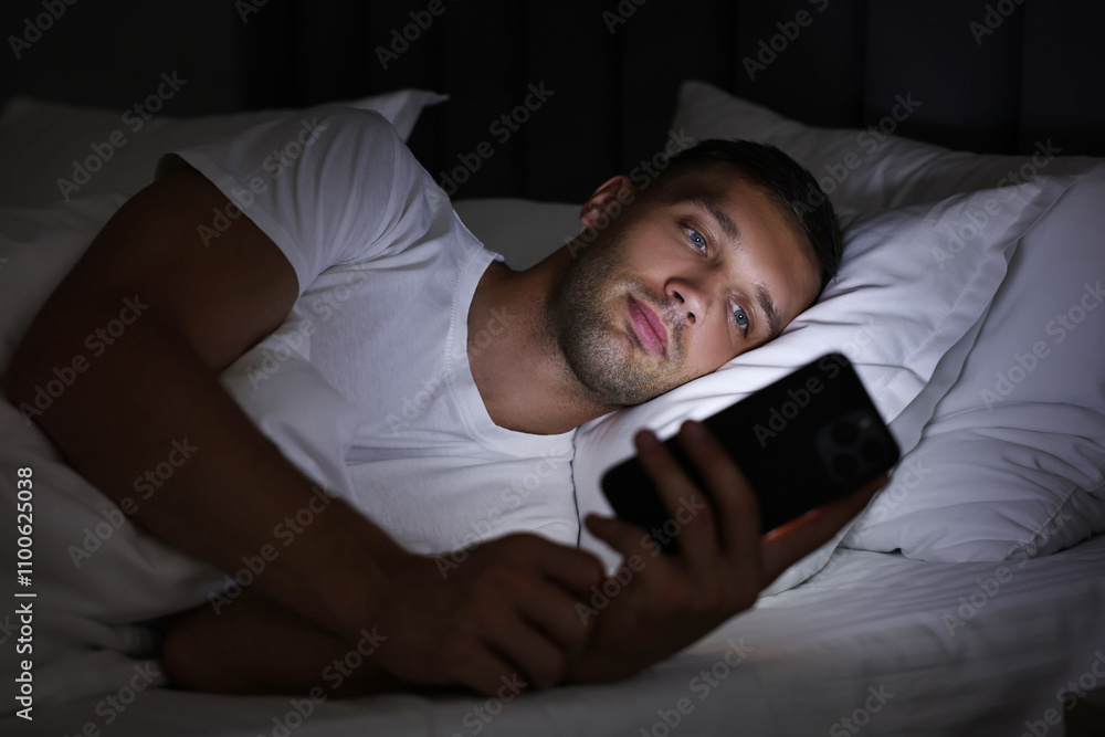 Bad habit. Man using smartphone in bed at night Bad habit. Man using smartphone in bed at night