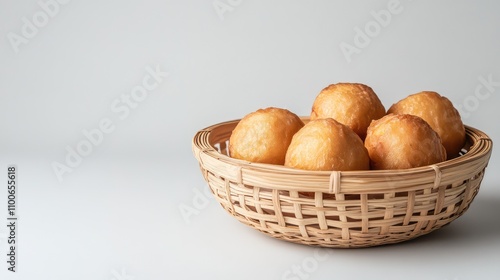 Freshly Fried Golden Dough Balls in a Woven Basket on White Surface