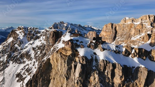 Aerial view of the Lagazuoi mountain ridge covered with snow and Rifugio Lagazuoi on the clifftop. Dolomite Alps, Italy
