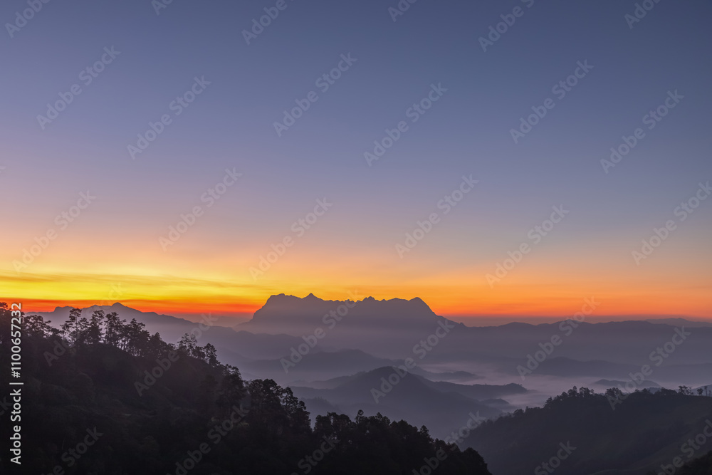 Obraz premium Early morning colourful sunset sky glowing over silhouetted mountains on the landscape