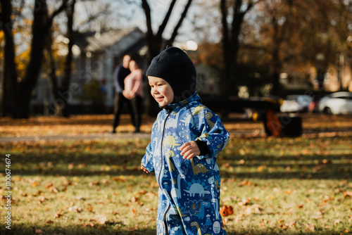 A joyful little boy in his winter coat and hat plays happily in the park, surrounded by the love and warmth of his smiling parents photo