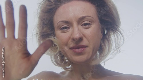 Mature woman looks back at her flection while touching water 