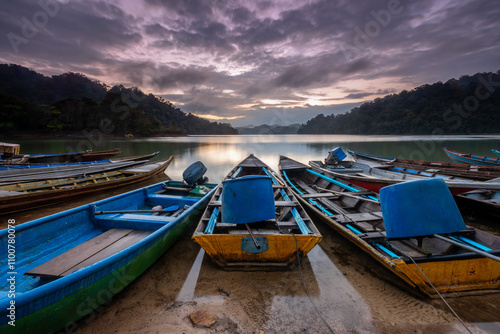 Fisherman boats docked peacefully along the calm waters of Gubir Lake at Sik Kedah, bathed in the soft glow of the morning light. A serene moment of lakeside beauty.