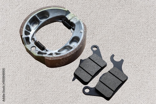 Front and rear drum and disc brake pads for motorcycle isolated on white cloth.