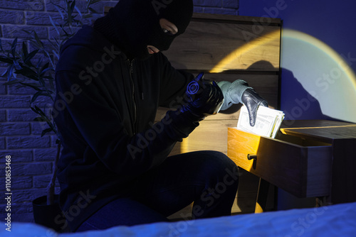 Female thief with flashlight in dark room photo