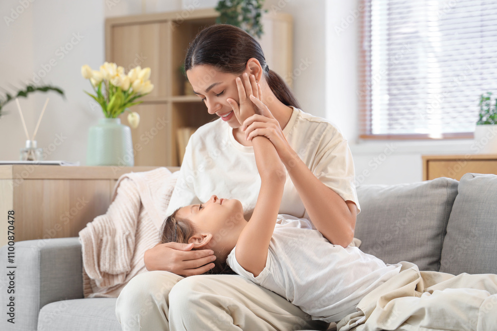 Embracing mother with her little daughter on sofa at home. International Hug Day Embracing mother with her little daughter on sofa at home. International Hug Day