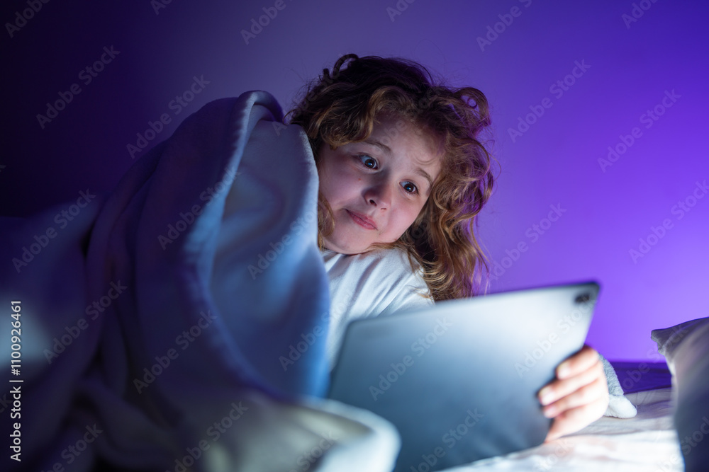Kids Bed time story in tablet. Kid lying on bed and surfing Internet on tablet in dark room. Boy reading Tablet in bed at night. E-book, story and kids app game. Kid using tablet before going to bed. Kids Bed time story in tablet. Kid lying on bed and surfing Internet on tablet in dark room. Boy reading Tablet in bed at night. E-book, story and kids app game. Kid using tablet before going to bed.