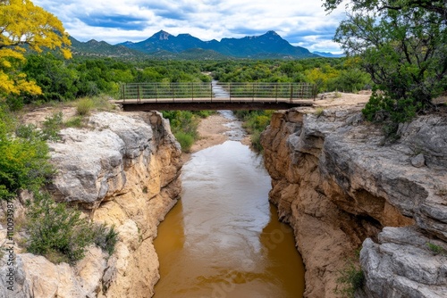 A river canyon forming a natural border, with steep cliffs and a suspension bridge connecting the two sides photo