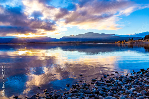 Golden reflections, tranquil rocky shoreline