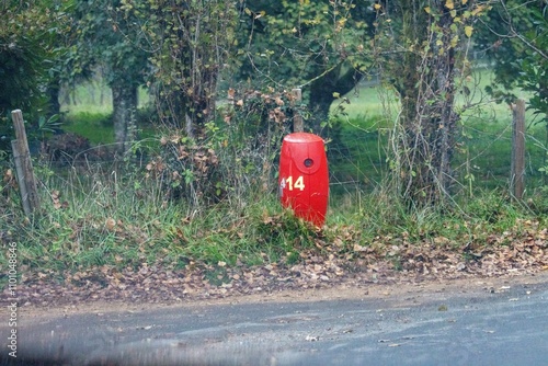 Red roadside marker amid autumn leaves in Dordogne countryside France photo