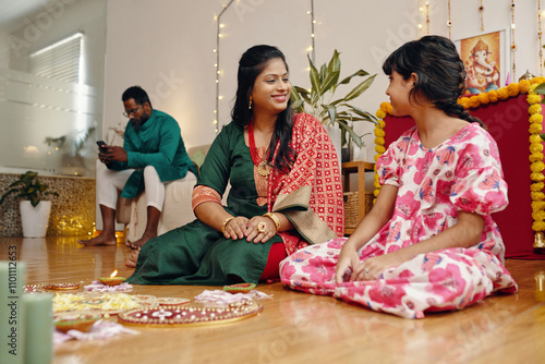 Family sitting and enjoying festive occasion in home decorated with lights and traditional items. Man is seated in back, while woman and girl smiling at each other photo