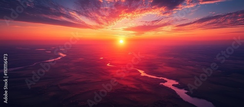 Microlight aircraft soaring above scenic landscape at sunset with vibrant sky and reflective river winding through the countryside photo