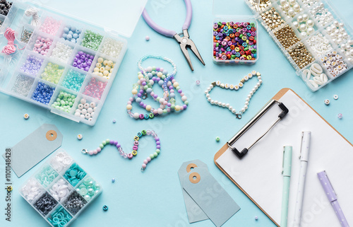 Colorful beads, pliers, clipboard and price tags arranged on blue surface for diy bracelet making