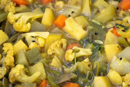 Close-up view of mix of vegetables as background, featuring cauliflower, carrots, beans, snake gourd, potatoes, pointed gourd, and cucumbers. photo