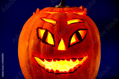 Halloween pumpkin with candle light inside on a dark blue background