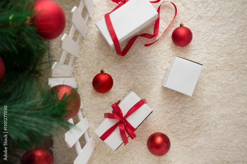 Obraz premium Christmas scene with red baubles and white gift boxes on a fluffy carpet beside a tree