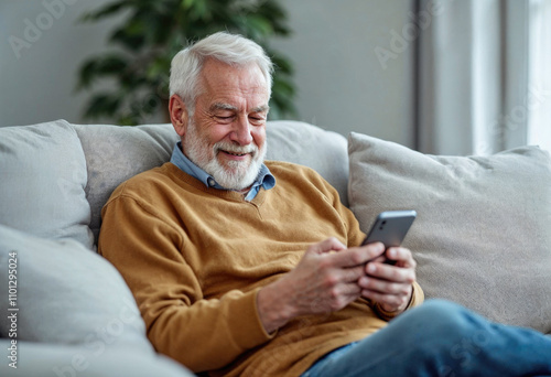 A man is sitting on a couch and smiling while holding a cell phone