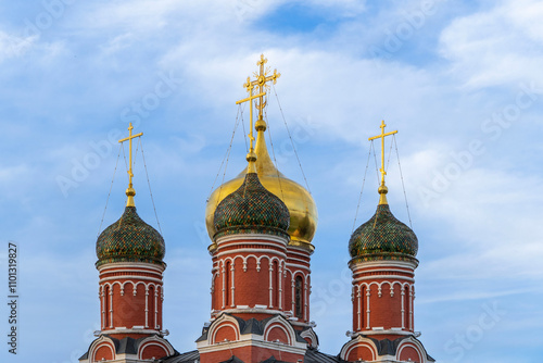 Domes of Moscow Orthodox Cathedral against background of blue summer sky. Golden dome is located in center. Three multi-colored domes arranged around golden dome. Moscow, Russia - June 14, 2024