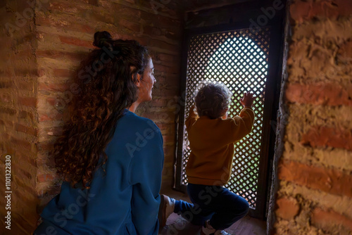 Mother and Toddler Inside the Keep of an Ancient Muslim Fortress at Sunset, Looking Through a Moorish Lattice photo