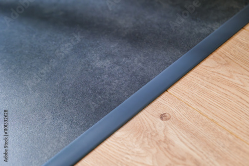 Anthracite expansion strip between ceramic tiles and floor panels. Aesthetic floor finishing. finishing strip. Interior