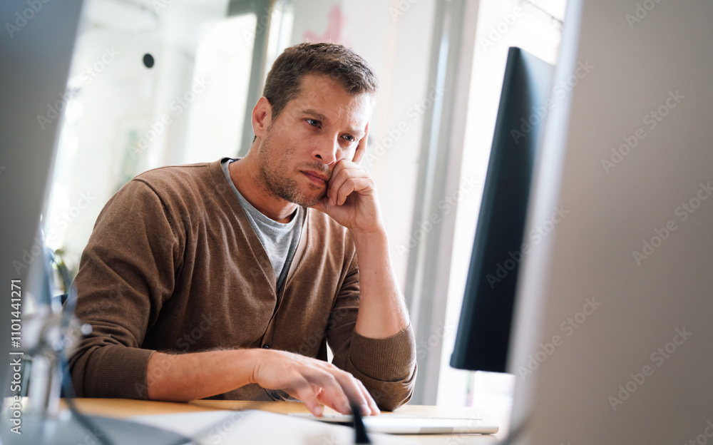 Portrait of a disappointed man programmer looking stressed out while working on a computer code Portrait of a disappointed man programmer looking stressed out while working on a computer code