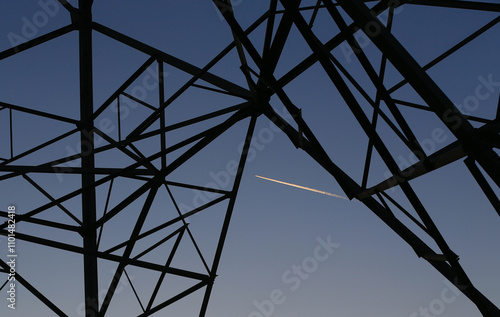 Many high-voltage power towers, silhouetted against the setting sun