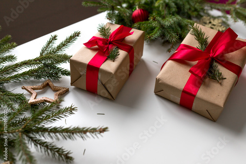 christmas gifts in craft paper and tied with a red ribbon. Christmas gift wrapping using eco-friendly materials and pine branches.