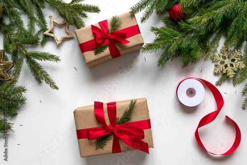 christmas gifts in craft paper and tied with a red ribbon. Christmas gift wrapping using eco-friendly materials and pine branches.