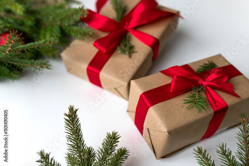 christmas gifts in craft paper and tied with a red ribbon. Christmas gift wrapping using eco-friendly materials and pine branches.