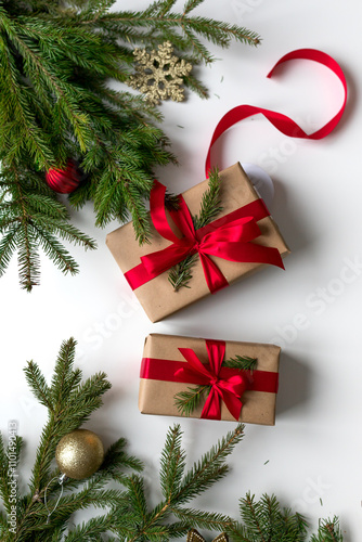 christmas gifts in craft paper and tied with a red ribbon. Christmas gift wrapping using eco-friendly materials and pine branches.