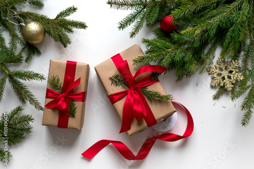 christmas gifts in craft paper and tied with a red ribbon. Christmas gift wrapping using eco-friendly materials and pine branches.