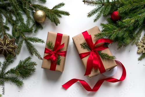christmas gifts in craft paper and tied with a red ribbon. Christmas gift wrapping using eco-friendly materials and pine branches.