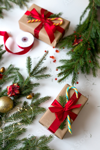 Christmas gifts in craft paper and tied with a red ribbon. Christmas gift wrapping using eco-friendly materials and pine branches