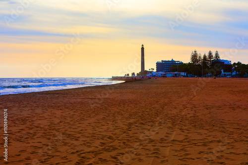 Obraz na płótnie Maspalomas lighthouse and beach at twilight, Gran Canaria, Canary Islands. Sandy beach during sunset with a tall lighthouse. Beach is with footprints in the sand, and the ocean waves against shore w salonie