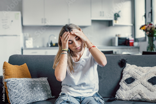 Depressed or tired teen girl feeling stress headache hurt pain sitting alone at home, upset sad heartbroken young woman regret pregnancy or abortion, troubled with problem or psychological trauma photo