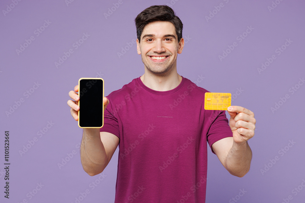 Young happy man he wears violet t-shirt casual clothes using blank screen mobile cell phone hold credit bank card doing online shopping order delivery booking tour isolated on plain purple background. Young happy man he wears violet t-shirt casual clothes using blank screen mobile cell phone hold credit bank card doing online shopping order delivery booking tour isolated on plain purple background.