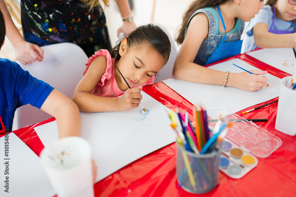 Obraz premium Elementary school art class: young students focused on watercolor painting and using colored pencils