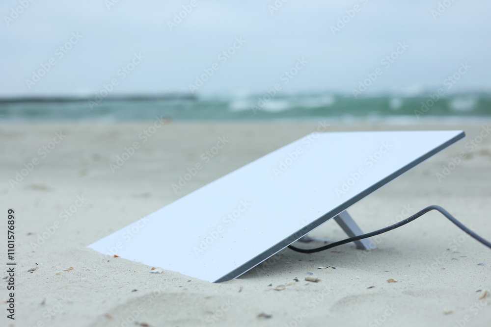 A Satellite Dish rests on the sandy beach under cloudy skies, blending nature and technology A Satellite Dish rests on the sandy beach under cloudy skies, blending nature and technology