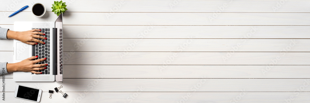 Female hands working on modern laptop. White wooden office desktop