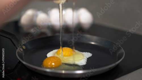 This is a closeup image of a perfectly frying egg on a hot skillet with several eggs visible in the background