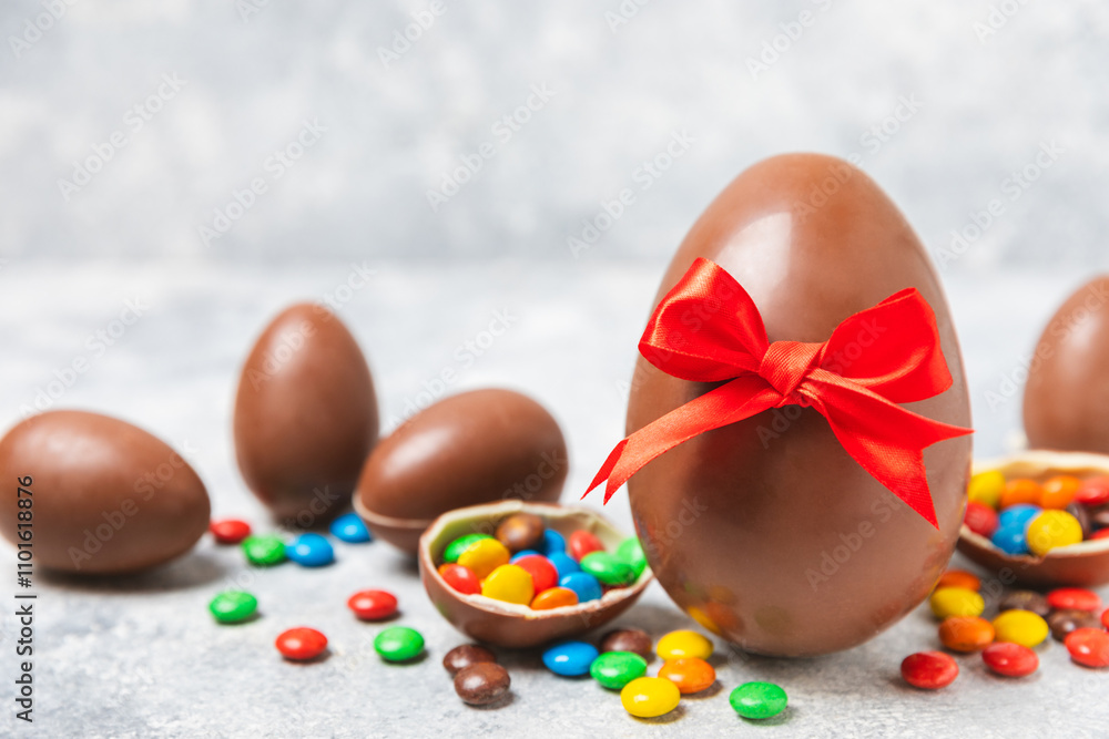 Obraz premium Easter chocolate egg on textured background. Easter celebration concept. Easter chocolate rabbit. Chocolate sweet eggs. Candies on textured wooden table. Space for text.Copy space. Gift. Banner.