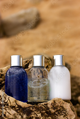 Wallpaper Mural Plastic bottles with natural cosmetic in travel containers - blue shower gel, shampoo with bubbles inside, body lotion in miniature containers against a brown stone rock background. Face body care.  Torontodigital.ca