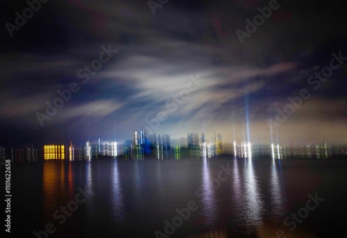 Fototapeta long exposure of a riverscape at evening when bluish sky was colorful and city lights are turning on beside the big river