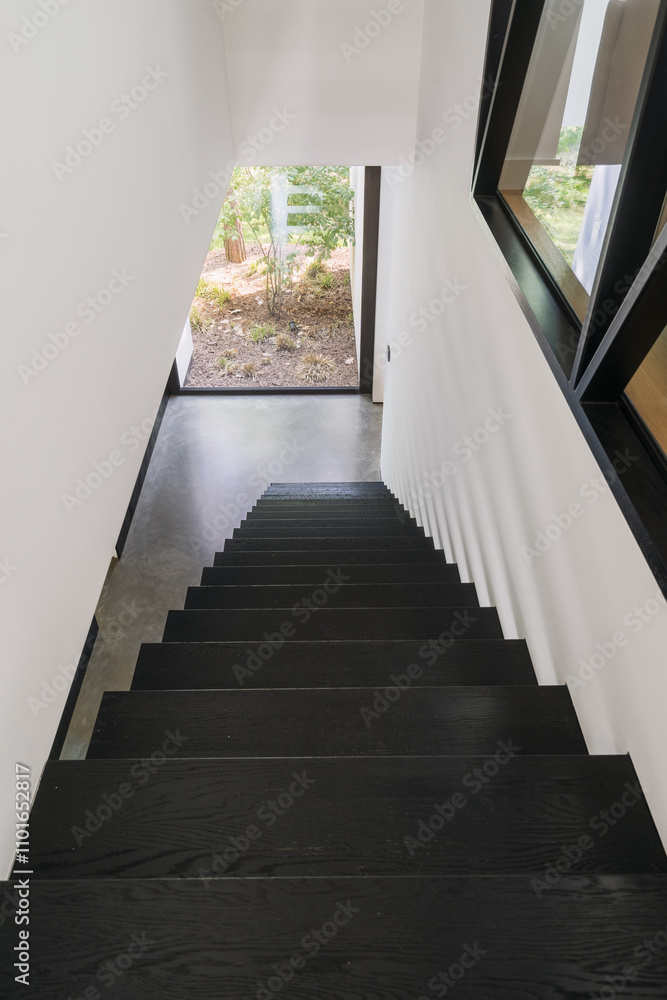 Modern staircase leading down to a serene outdoor space in residential home Modern staircase leading down to a serene outdoor space in residential home