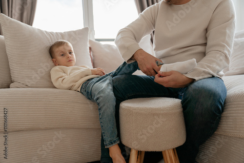 Dad slowly pulls down and pulls the white socks off the baby's feet. photo