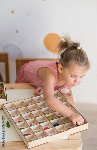 little girl playing sorter at the table. Educational boards for Color and Shapes sorting for toddler. Learning through play. Developing Montessori activities. photo